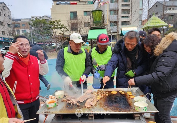 카페거리 윷놀이 행사에서 지역 주민과 지역구 이오수 도의원이 삼겹살 돼지고기를 굽고 있다.